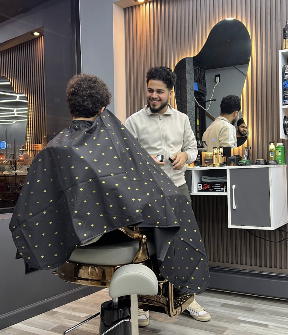 A Sully Cutz barber smiling with a client in the gold barber chair